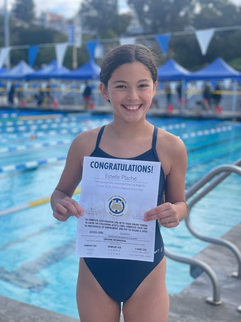 Junior Lifeguard candidate proudly holding her completion certificate