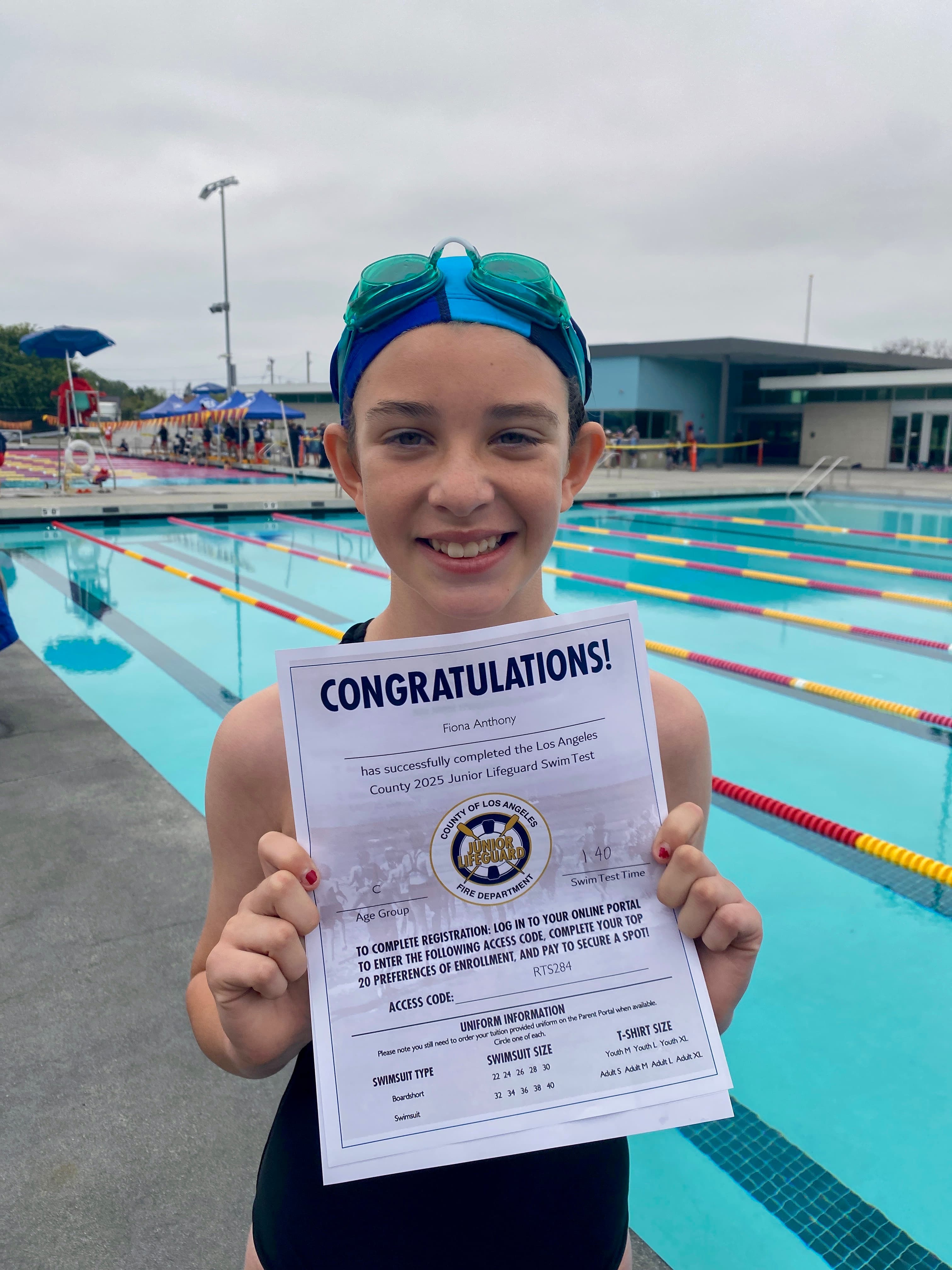 Junior Lifeguard candidate with goggles holding her swim test certificate